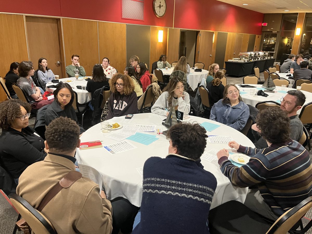 Undergraduates and graduate students in conversation at multiple round tables