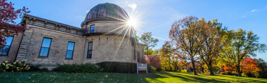 Sunlight shines from behind Washburn Observatory during autumn