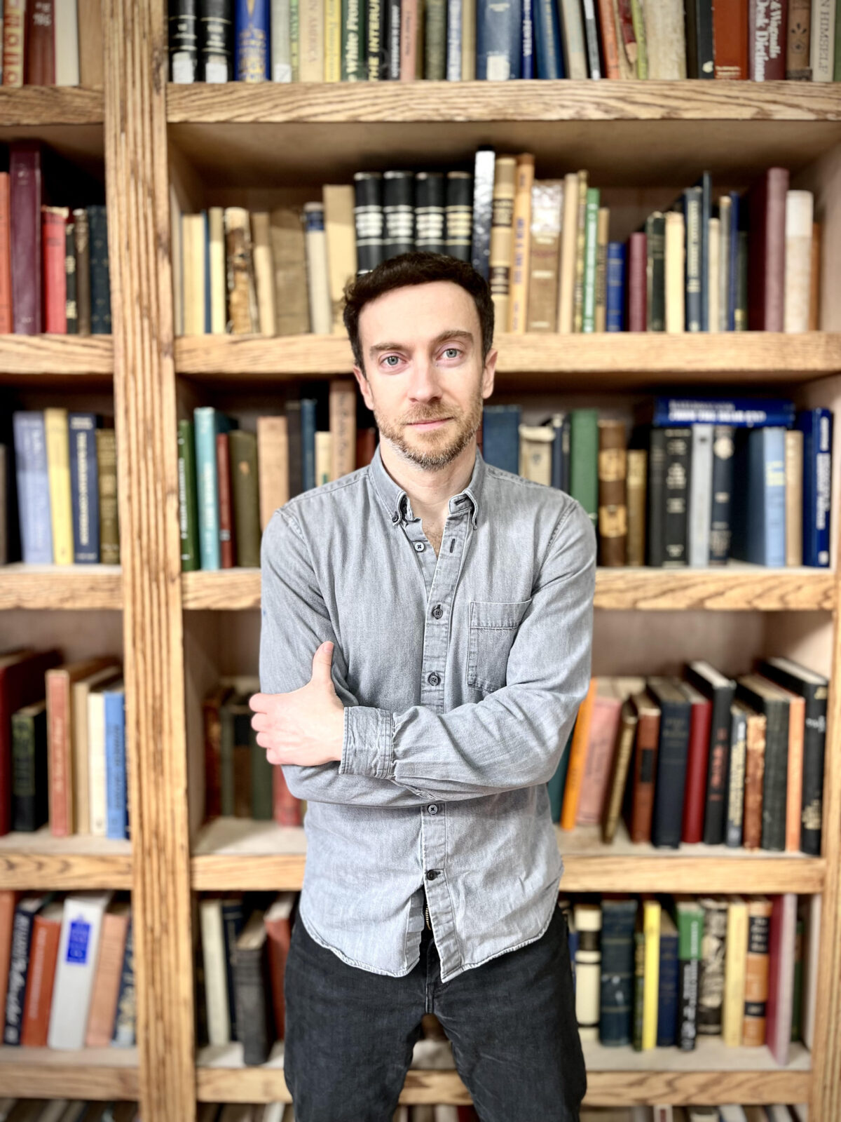 Author Eliot Stein standing in front of bookshelves.